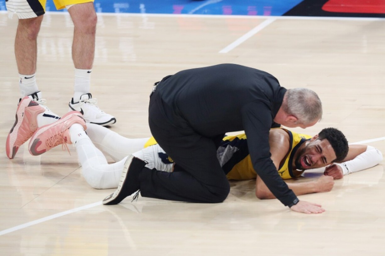 Indiana's Tyrese Haliburton grimaces in pain on the court as a trainer checks him for what proved to be a torn right Achilles tendon