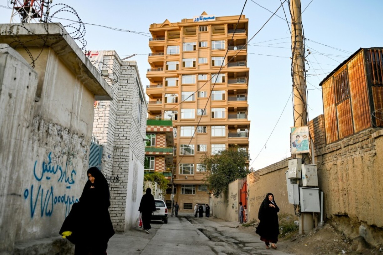 Afghan women walking along a street near a Kabul residential building due for demolition