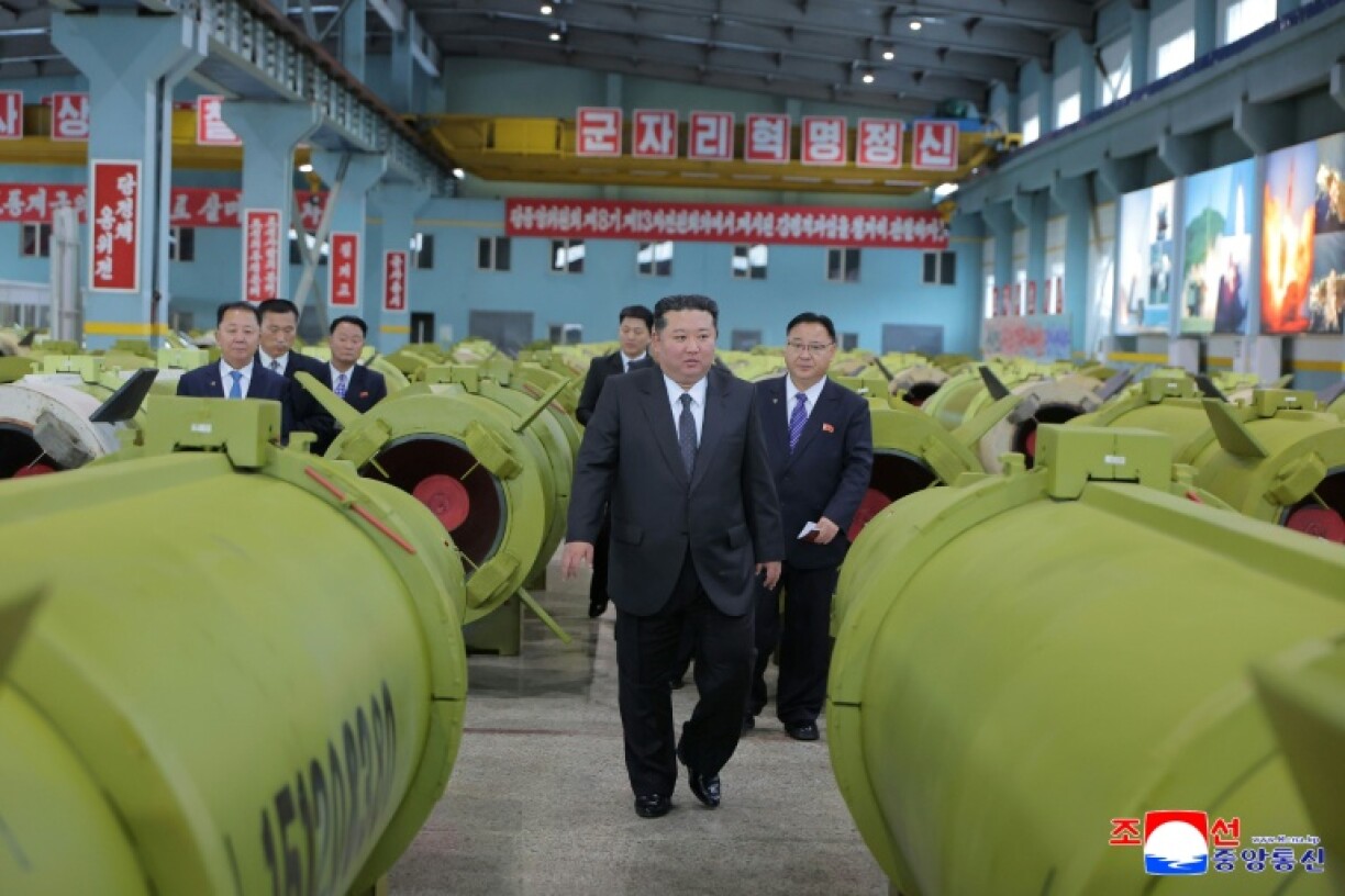Cette photo non datée, publiée par l'agence de presse officielle nord-coréenne KCNA le 26 décembre 2025, montre le dirigeant nord-coréen Kim Jong Un (c) en visite dans une usine de production de missiles et d'obus
