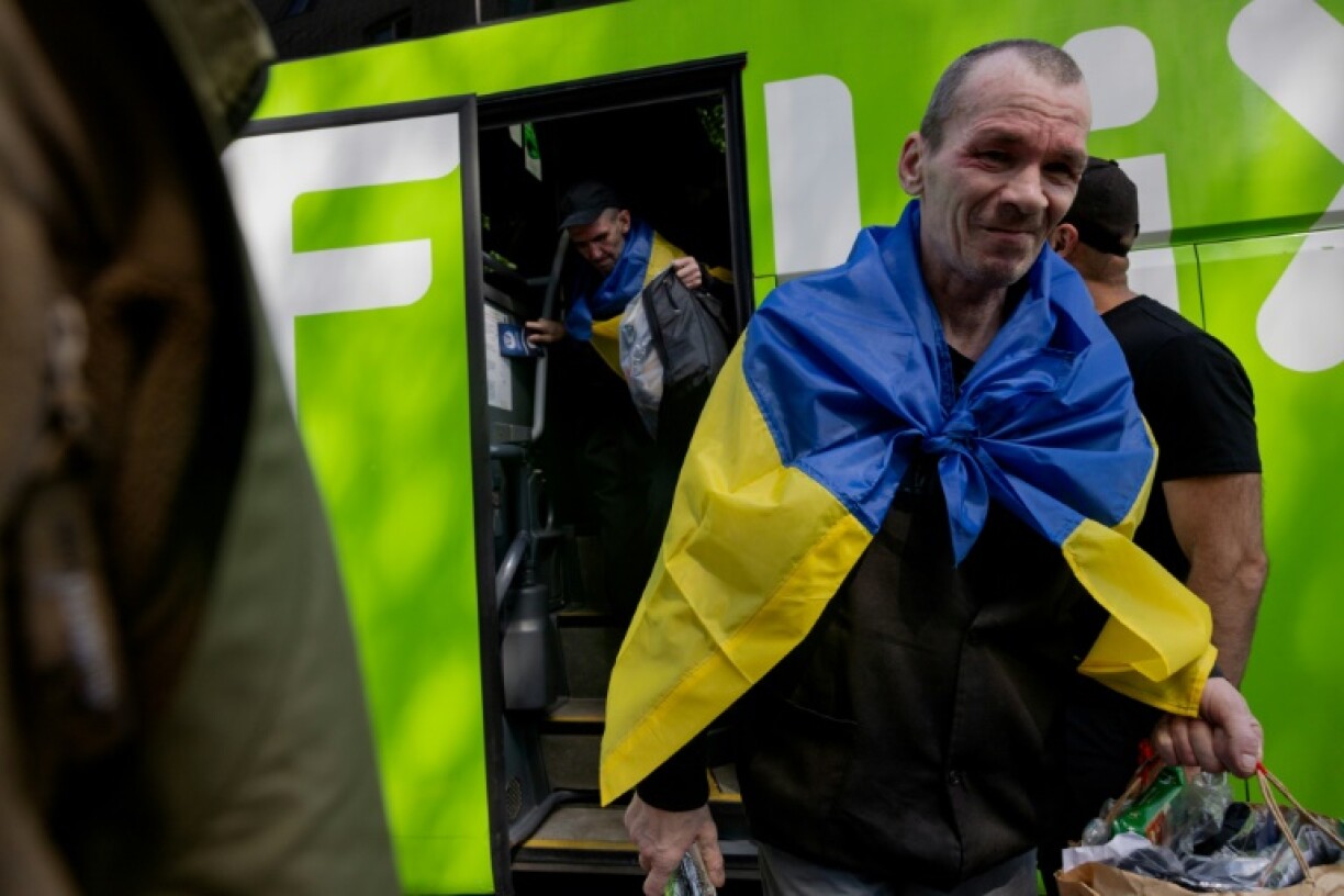 A Ukrainian soldier freed by Russia gets off a bus bringing him home as part of the third exchange this week