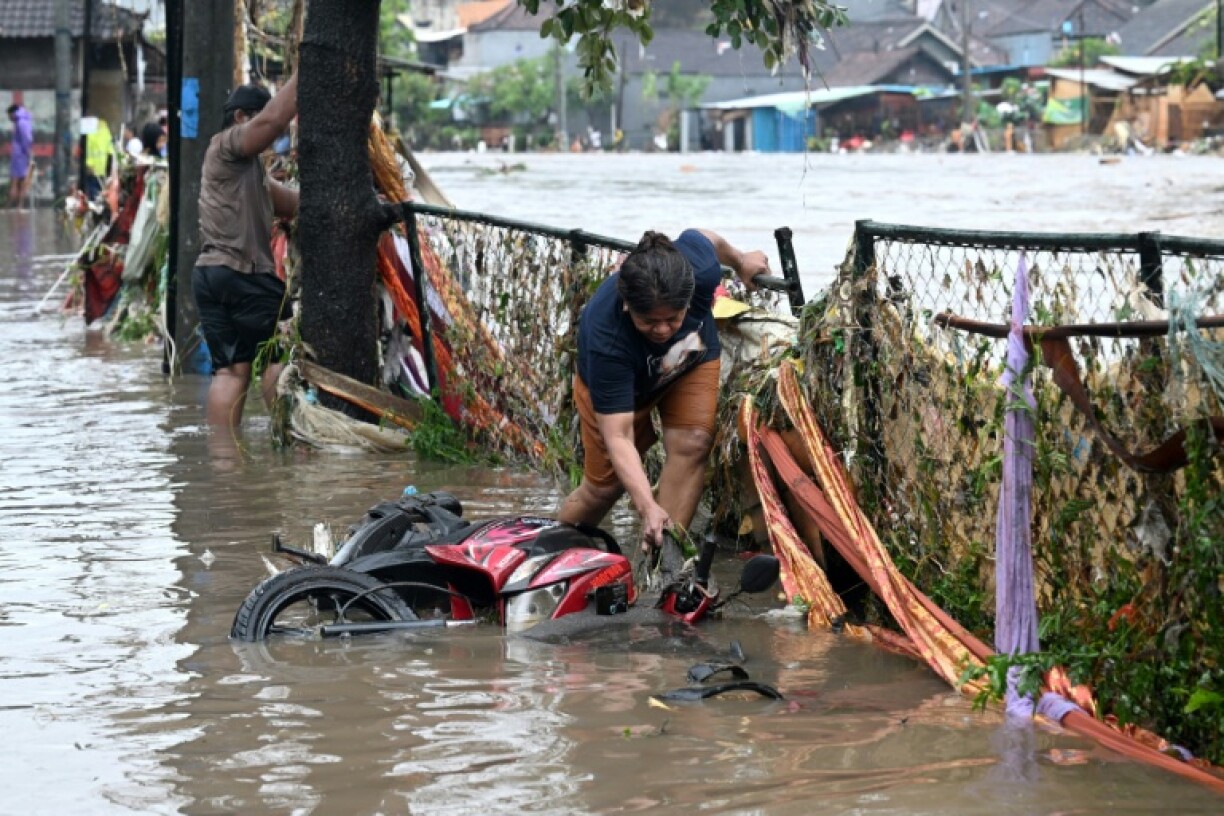 Une habitante touchée par les inondations redresse une moto immergée dans son quartier après de fortes pluie, à Denpasar, sur l’île indonésienne de Bali, le 10 septembre 2025