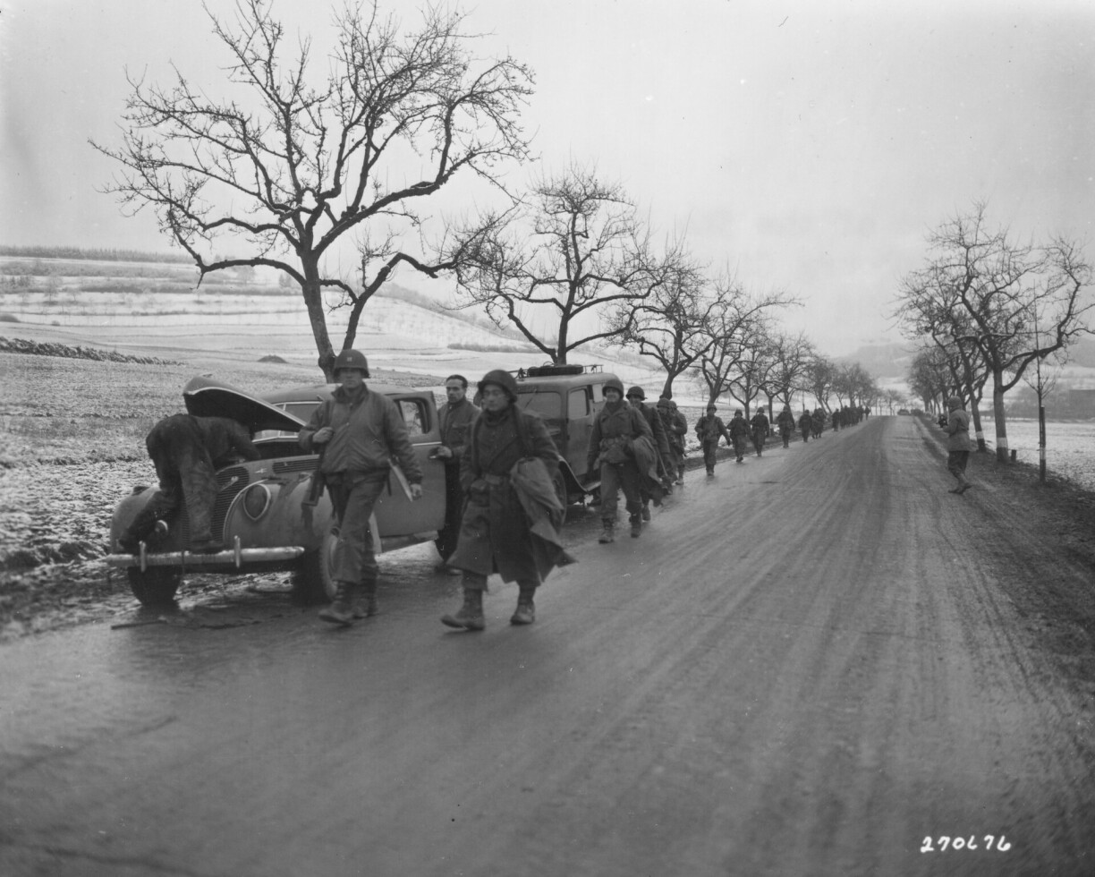 U.S. troops of the 5th Infantry Division, U.S. Third Army, Luxembourg, advance through wintry-looking countryside on their way to the frontlines. 22 December, 1944.