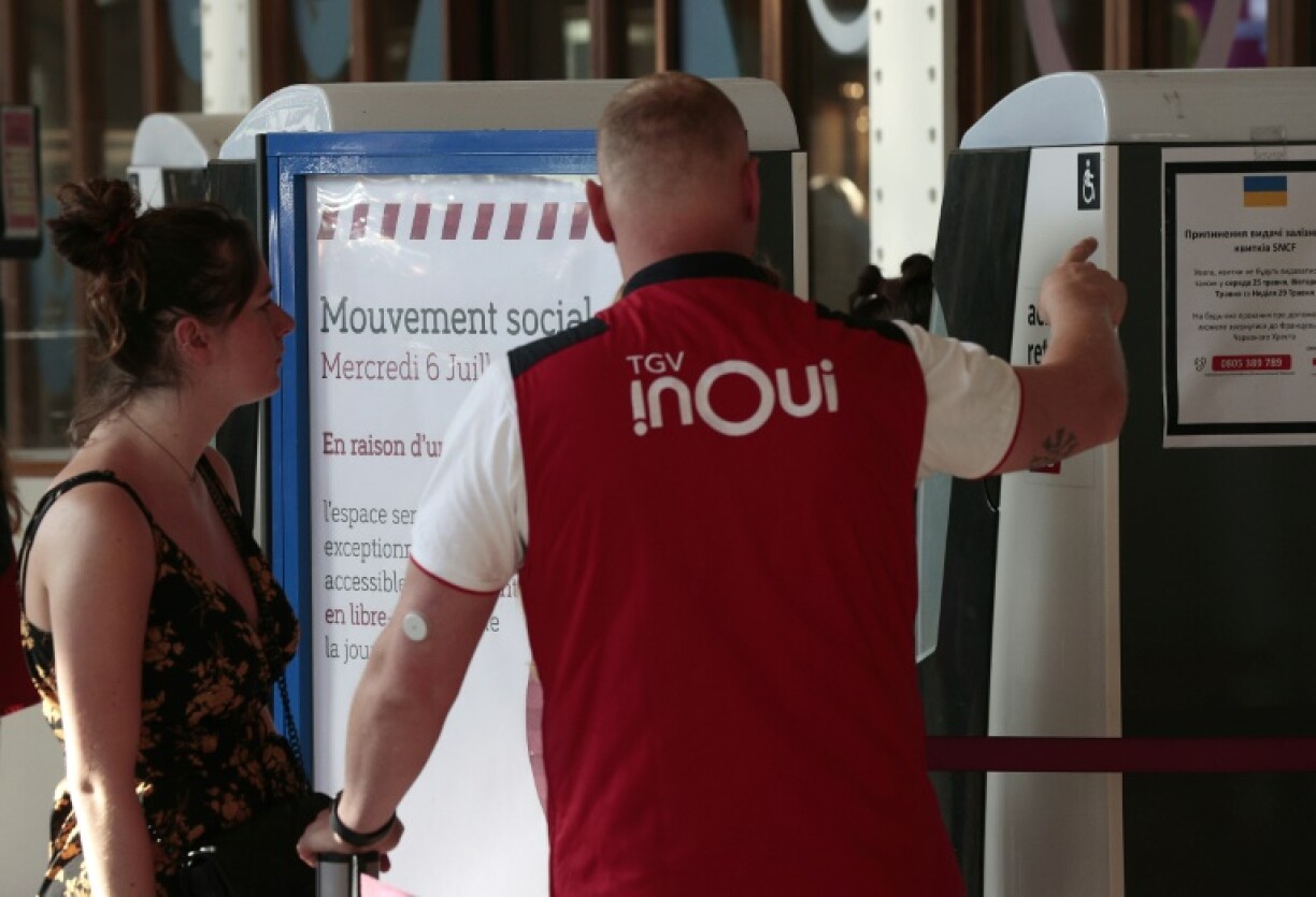 Un employé de la SNCF donne des informations à une passagère Gare de Lyon à Paris, le 6 juillet 2022, alors qu'une grève affecte la circulation des trains