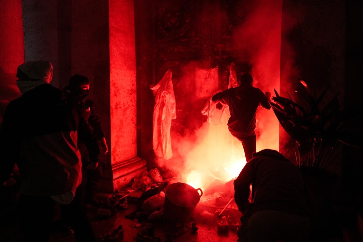 Des manifestants donnent des coups de pied à l'entrée de l'hôtel de ville alors qu'une fusée éclairante est allumée lors d'une manifestation pour exiger la démission du président régional de Valence, Carlos Mazon, à Valence.