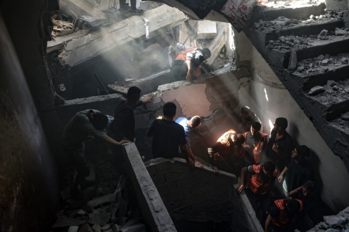 Residents and rescuers inside a building hit by an Israeli strike in Gaza City's Shujaiya district on April 10