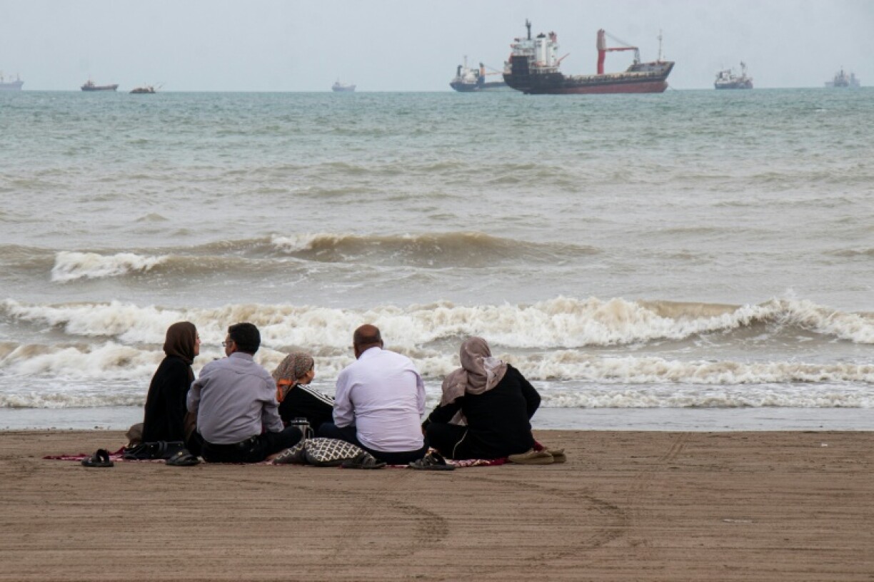 Cette photo diffusée par l'agence de presse iranienne Isna le 24 avril 2026 montre des Iraniens sur une plage bordant le détroit d'Ormuz