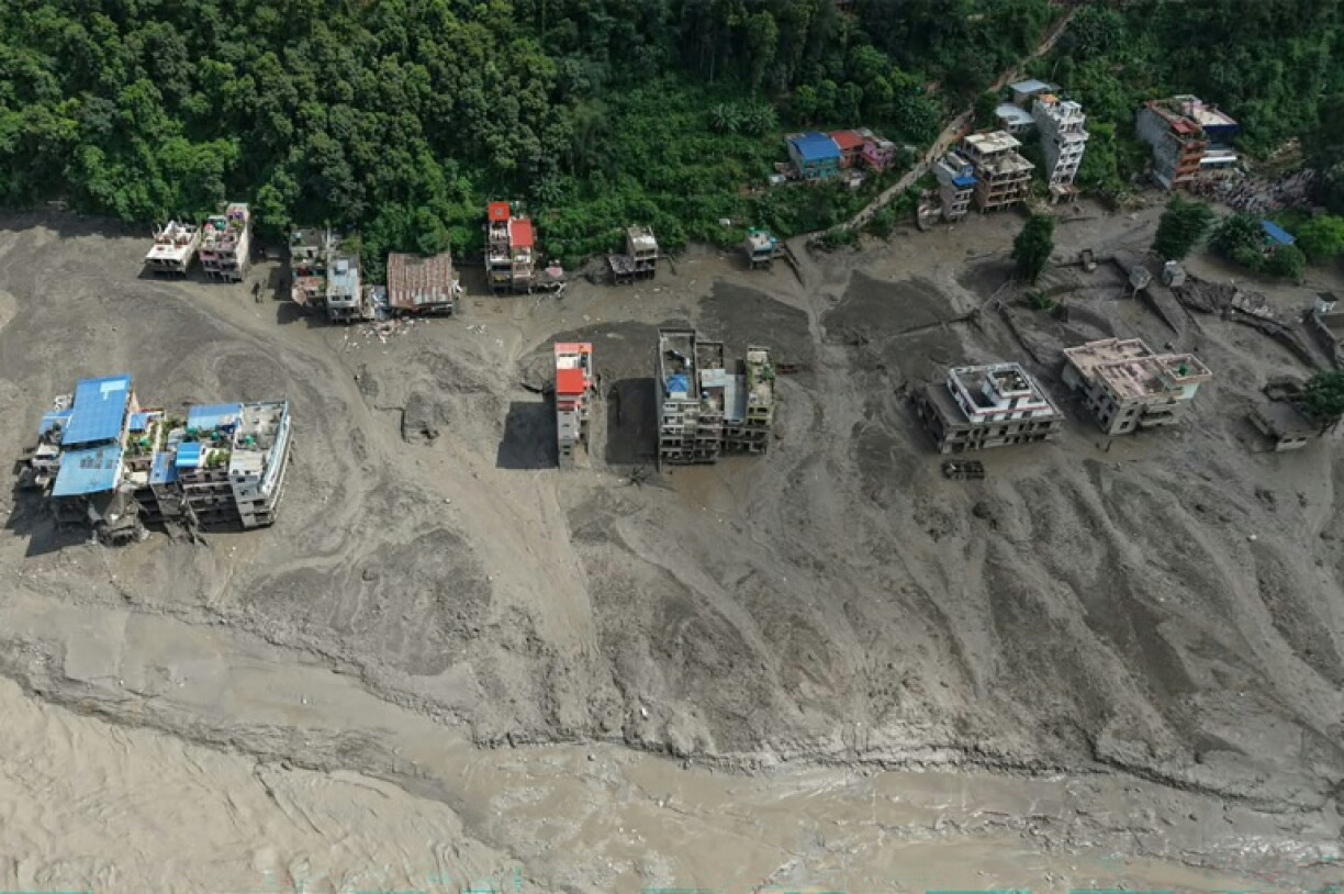 Des maisons sont partiellement submergées par une eau boueuse le long d'une rivière après des crues soudaines à Trishuli Bazar, dans le district de Nuwakot au Népal, le 26 août 2026.
