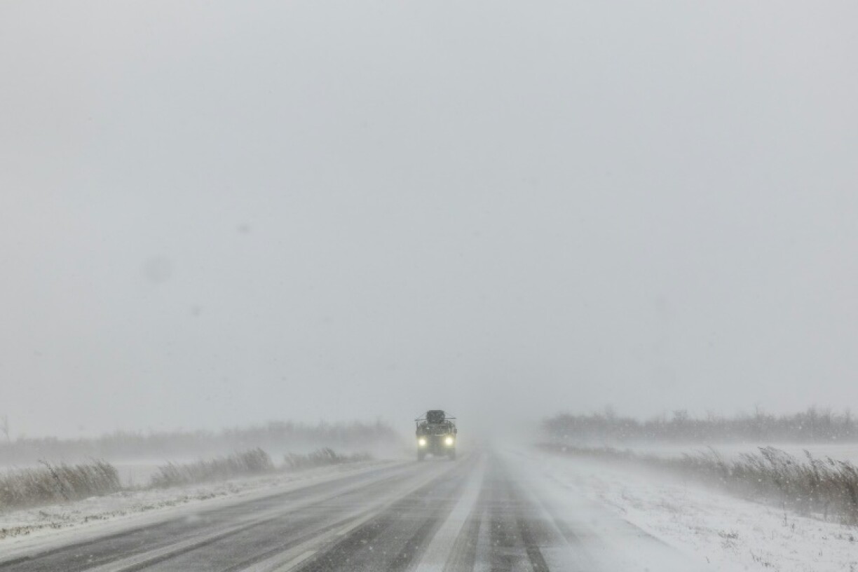 A Ukrainian armoured military vehicle drives along a road during snowfall in the eastern Donetsk region