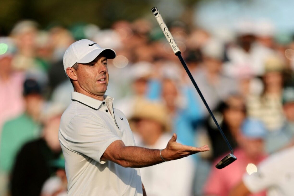 Rory McIlroy of Northern Ireland throws and catches his putter on the 18th green after firing a 66 to take the lead after the third round o the Masters