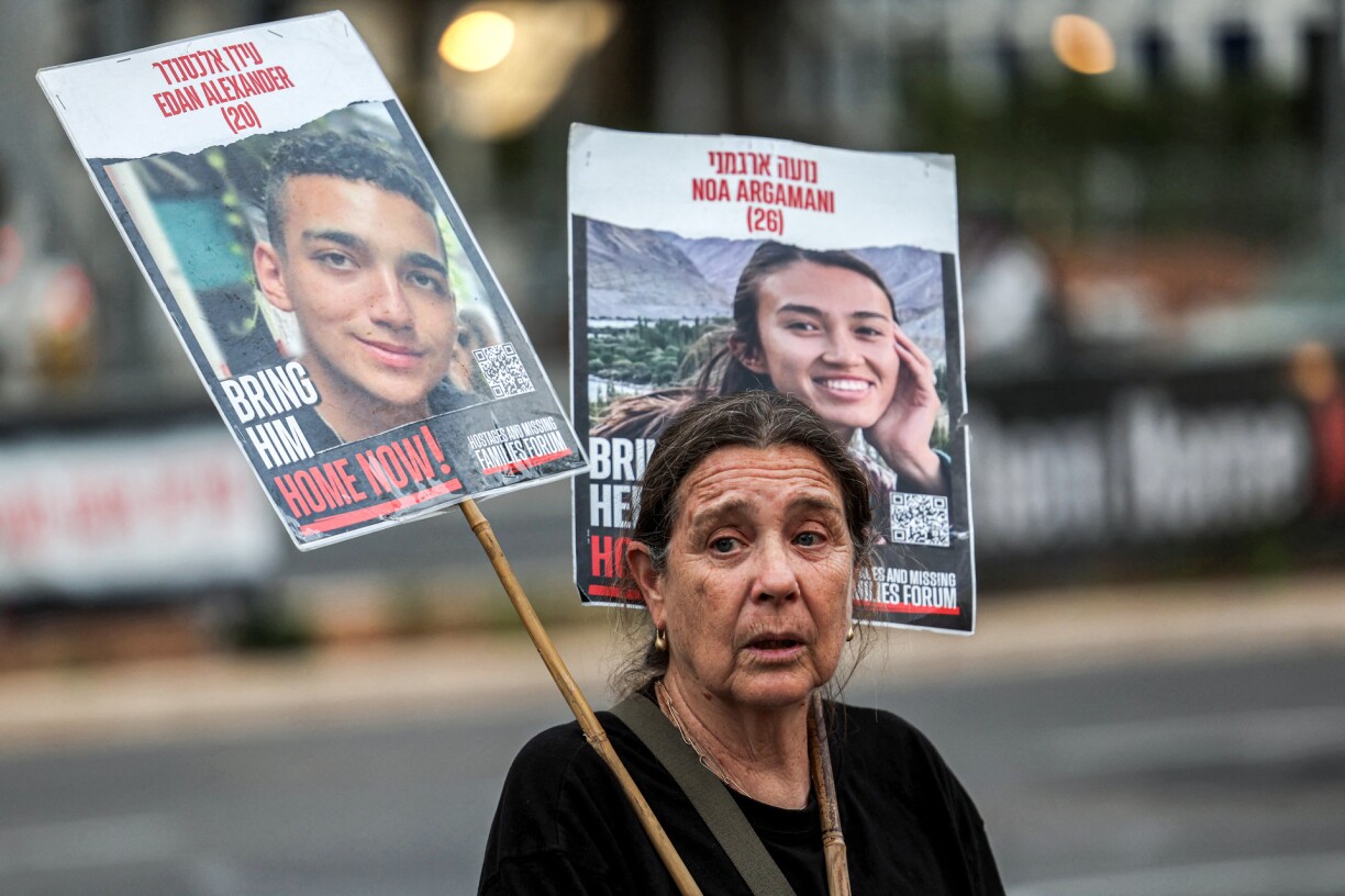 A woman holds signs identifying Edan Alexander (20) and Noa Argamani (26), two of the hostages taken captive by Palestinian militants in the Gaza Strip during the October 7 attacks, during a demonstration by hostages' relatives and supporters outside the Kirya base which houses the Israeli defence ministry headquarters in Tel Aviv on April 18, 2024 amid the ongoing conflict in the Palestinian territory between Israel and the militant group Hamas.