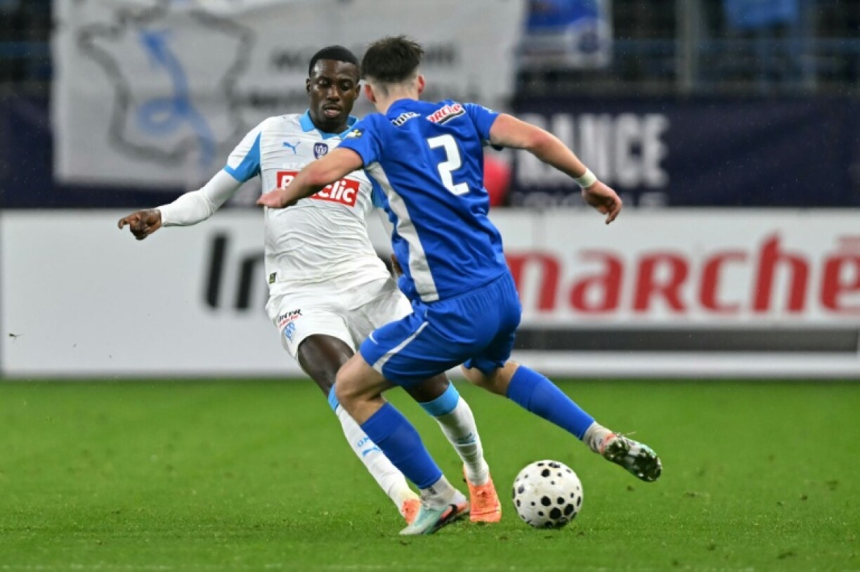 Le Marseillais Timothy Weah (G) et le défenseur de Bayeux Quentin Mayette lors du 16e de finale de la Coupe de France remporté par l'OM 9-0, le 13 janvier 2026 à Caen