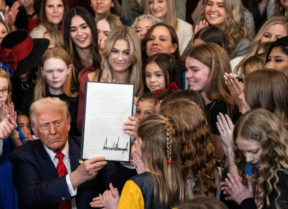 US President Donald Trump holds up a newly signed executive order that seeks to ban transgender female athletes from participating in women's sports