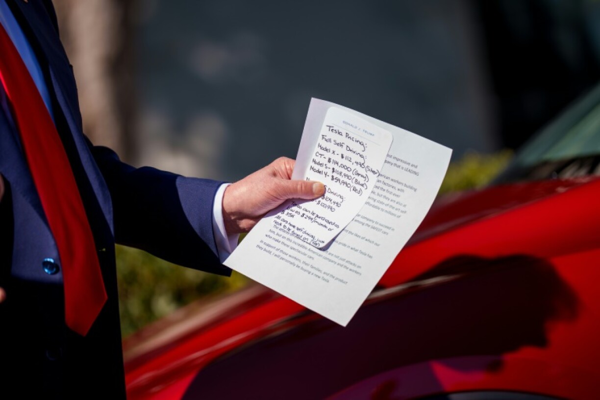 US President Donald Trump holds notes on the pricing of Tesla vehicles as he delivers remarks on the South Lawn of the White House, where he said he would purchase one of the company's electric cars