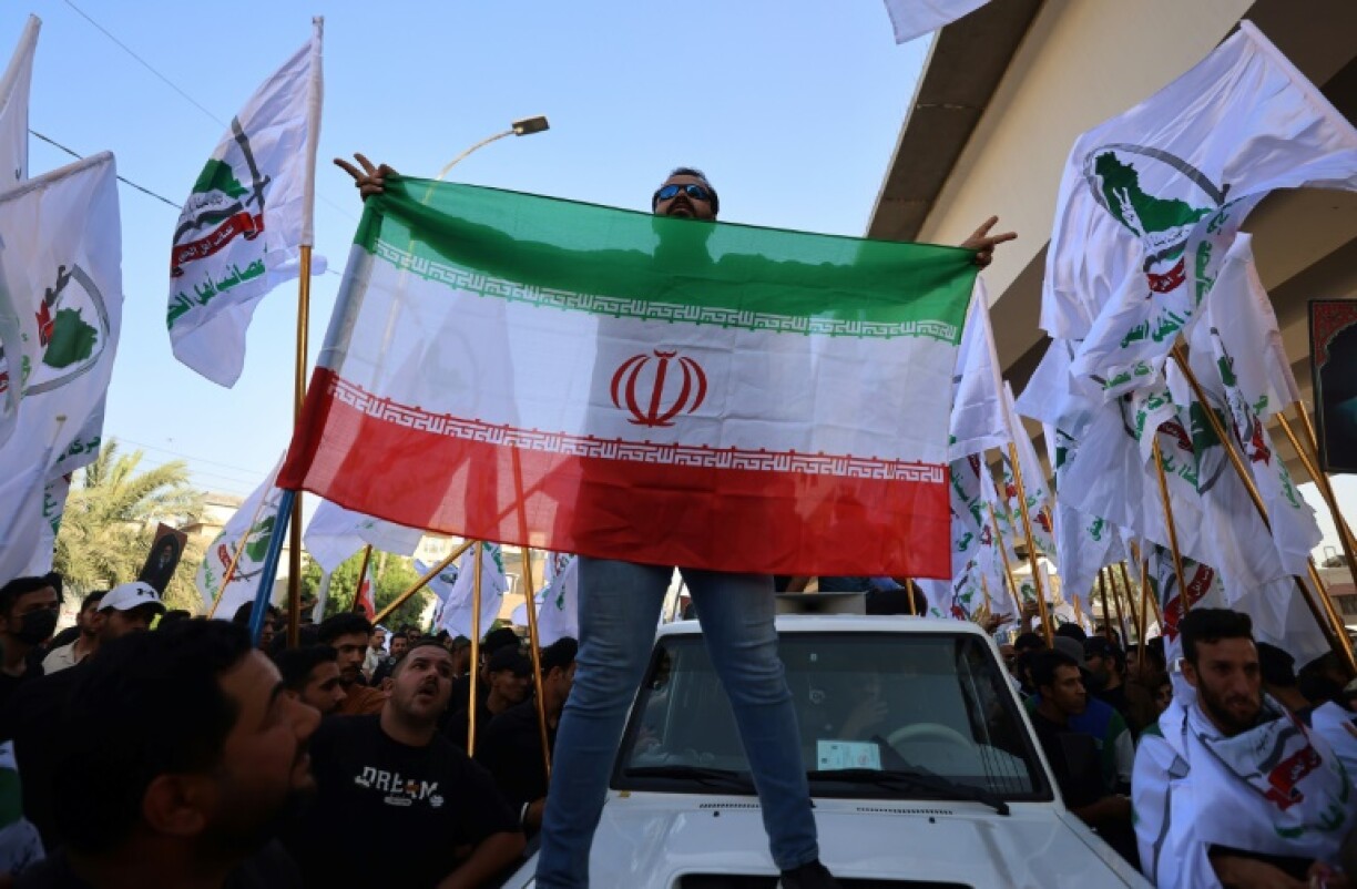 A man holds the Iranian flag as supporters of Iraqi pro-Iran groups demonstrate in Baghdad near the Green Zone