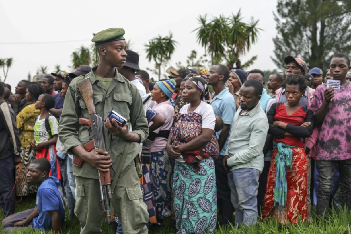 A member of the M23 armed group stands by as Goma residents listen to an address by local leaders