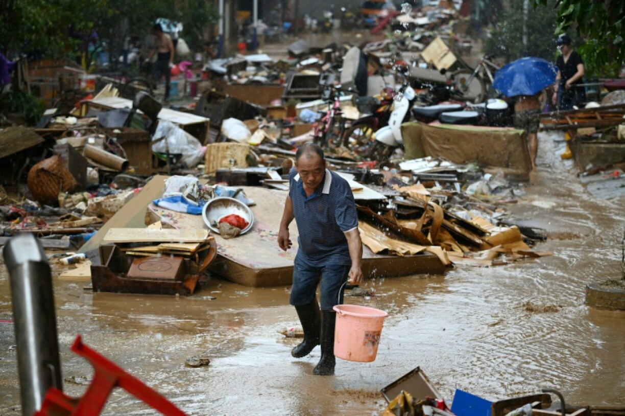 Un habitant récupère de l'eau de pluie dans une zone inondée après la rupture d'un réservoir près de Gantang, dans la région du Guangxi, le 9 juillet 2026 dans le sud-ouest de la Chine