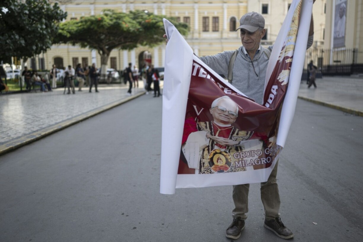 A man opens a banner with the image of Pope Leo XIV in front of the Chiclayo's cathedral, northern Peru