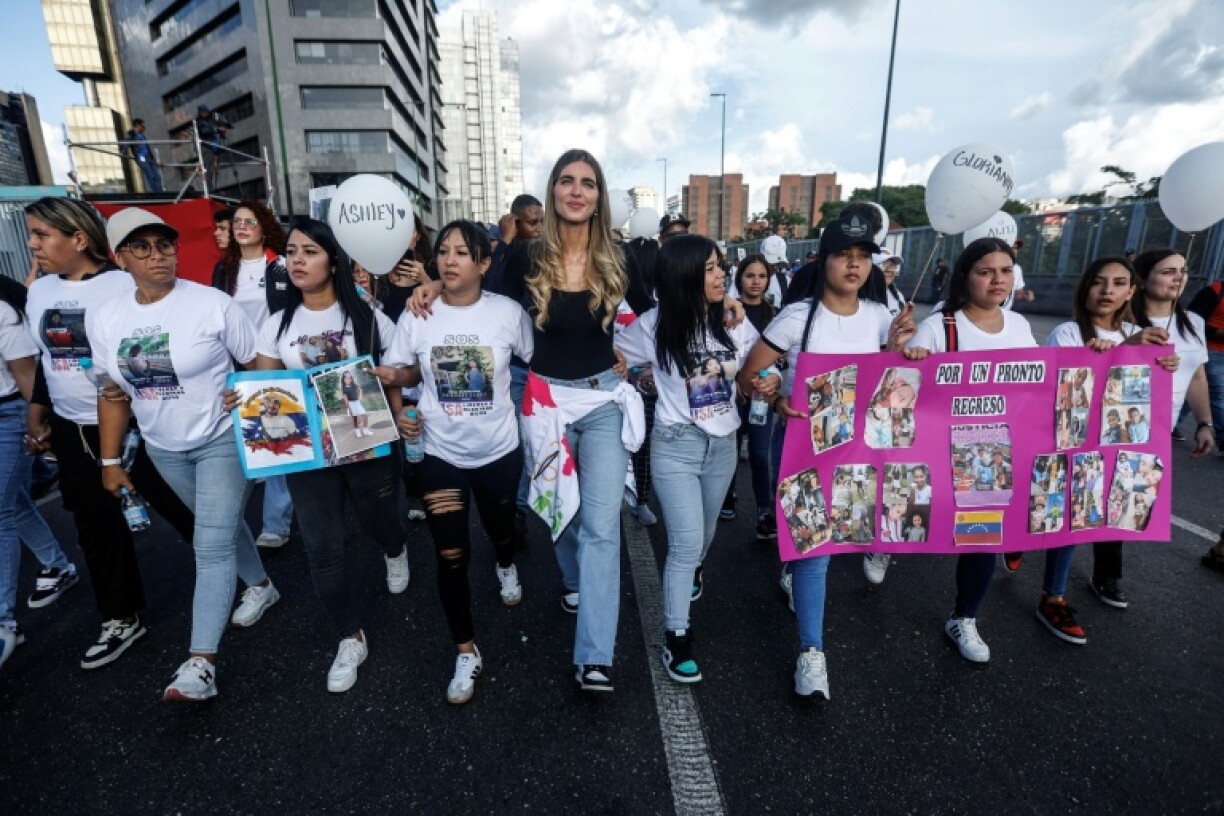 Camila Fabri Saab (C) walks with women showing photos of children who remain in the US after being separated from their parents