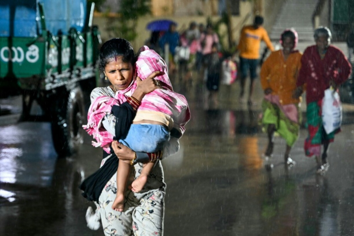 A woman carries her child to a relief shelter in Andhra Pradesh's Kakinada as cyclone Arnab bears down