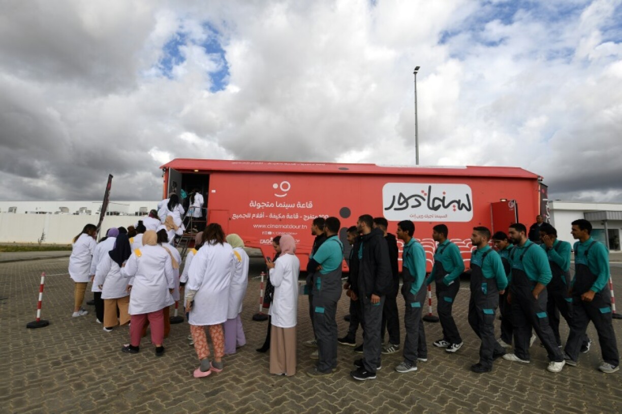 Factory workers line up to watch a film at CinemaTdour's mobile theatre, in Tunisia's town of Djemmal