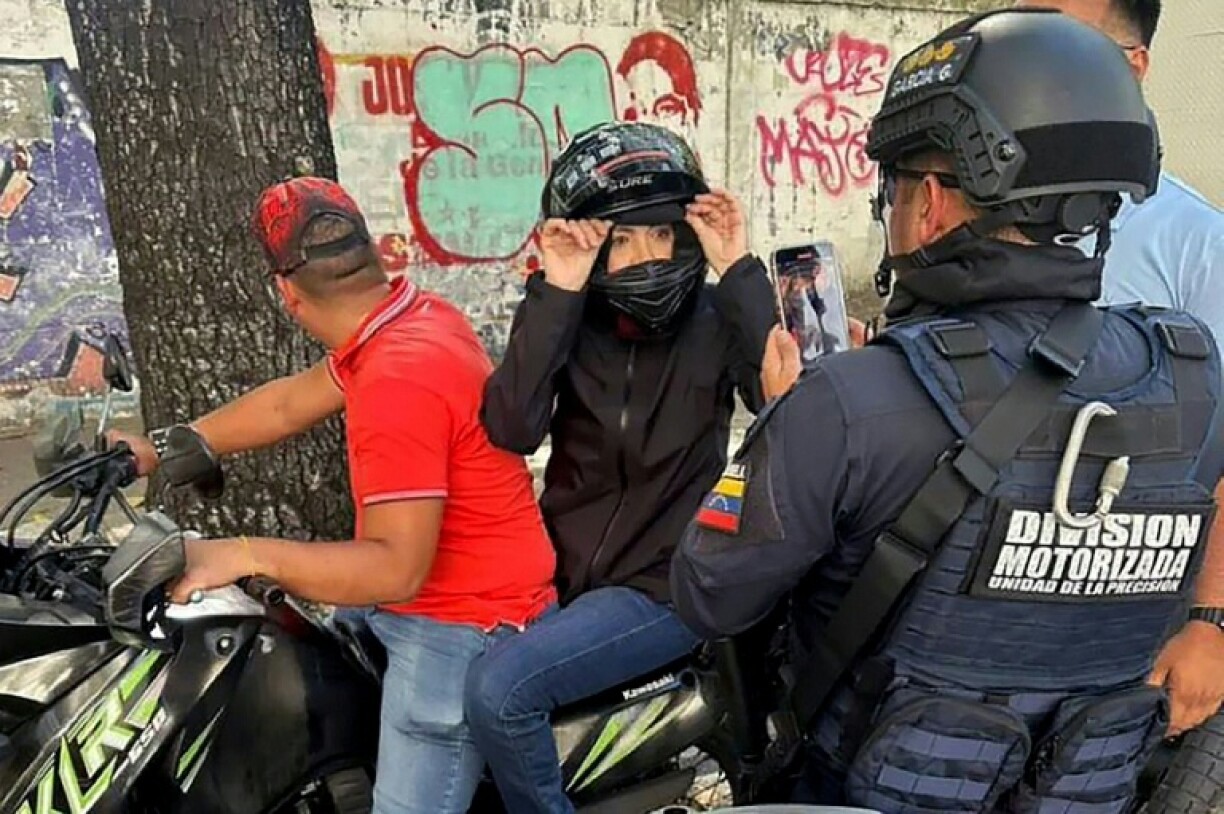 Handout picture released by Agencia Venezuela News showing Venezuelan opposition leader Maria Corina Machado being filmed by a National Police officer after delivering a speech during a demonstration called by the opposition on the eve of the presidential inauguration, in Caracas on January 9, 2025.
