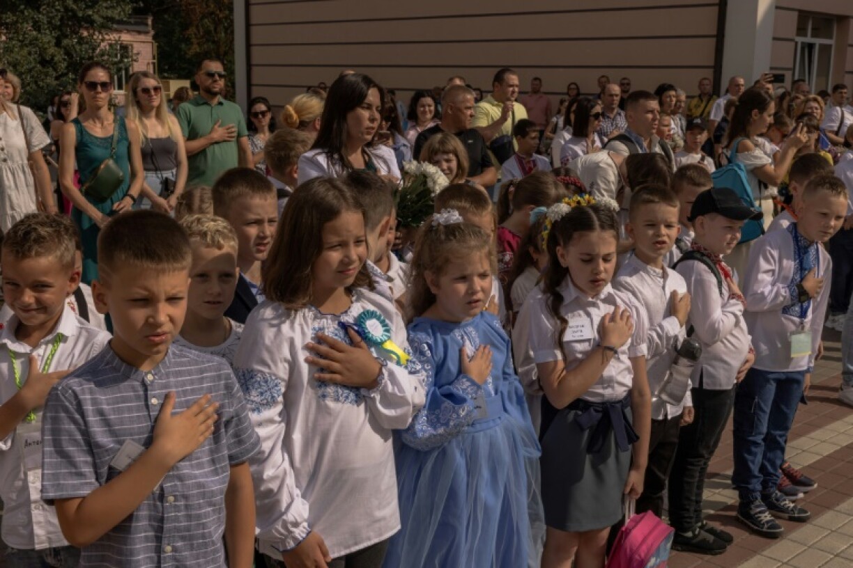 Des enfants ukraniens chantent l'hymne national avec leurs enseignants et leurs familles lors de la rentrée des classes, le 1er septembre 2023 à Irpin, dans les environs de Kiev