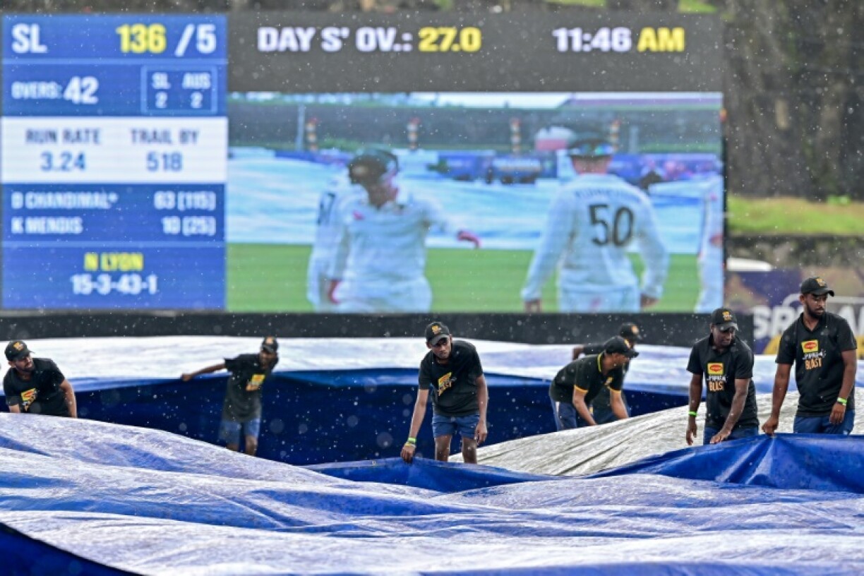 Groundsmen cover the field as rain halts play during the third day of the first Test between Sri Lanka and Australia in Galle