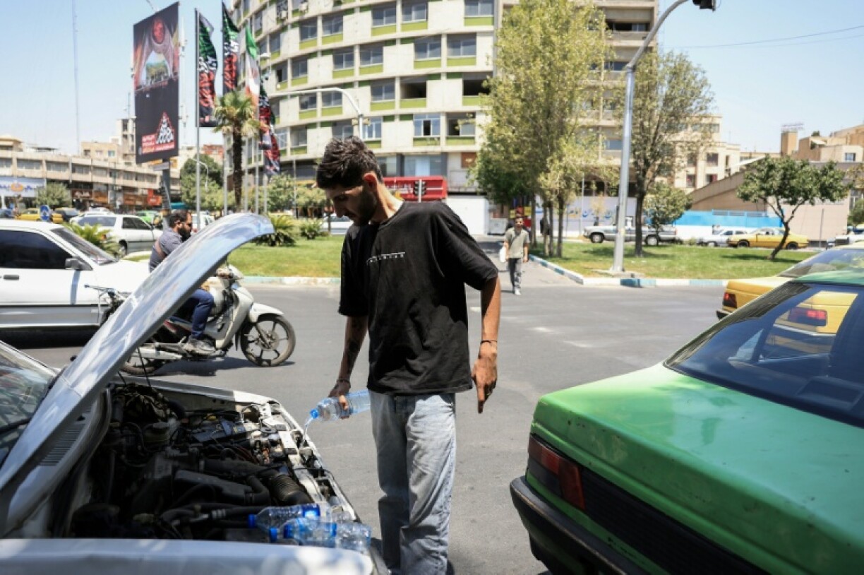 An Iranian taxi driver tries to cool down his engine after his radiator overheated in the soaring temperatures in Tehran.