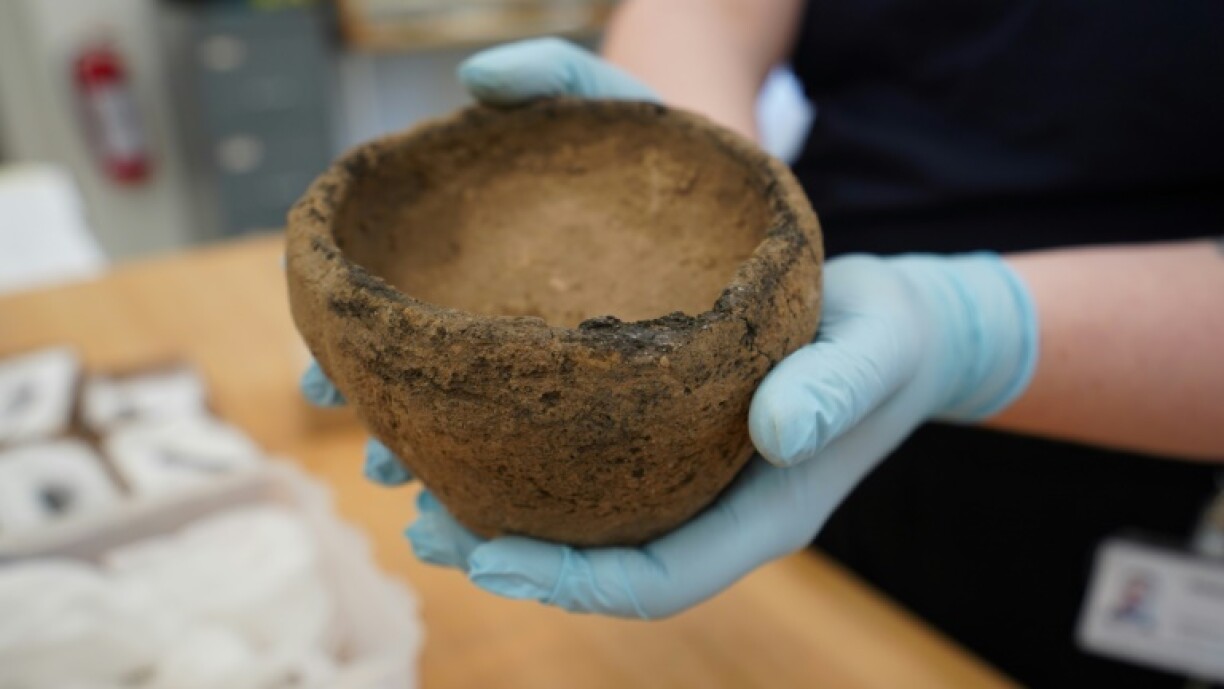 A museum conservator holds a Viking Age ceramic bowl discovered at the site