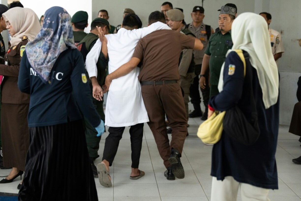 A man (C, in white), found guilty of sexual relations with another man under the strict Islamic sharia law, is helped after being publicly flogged in Banda Aceh