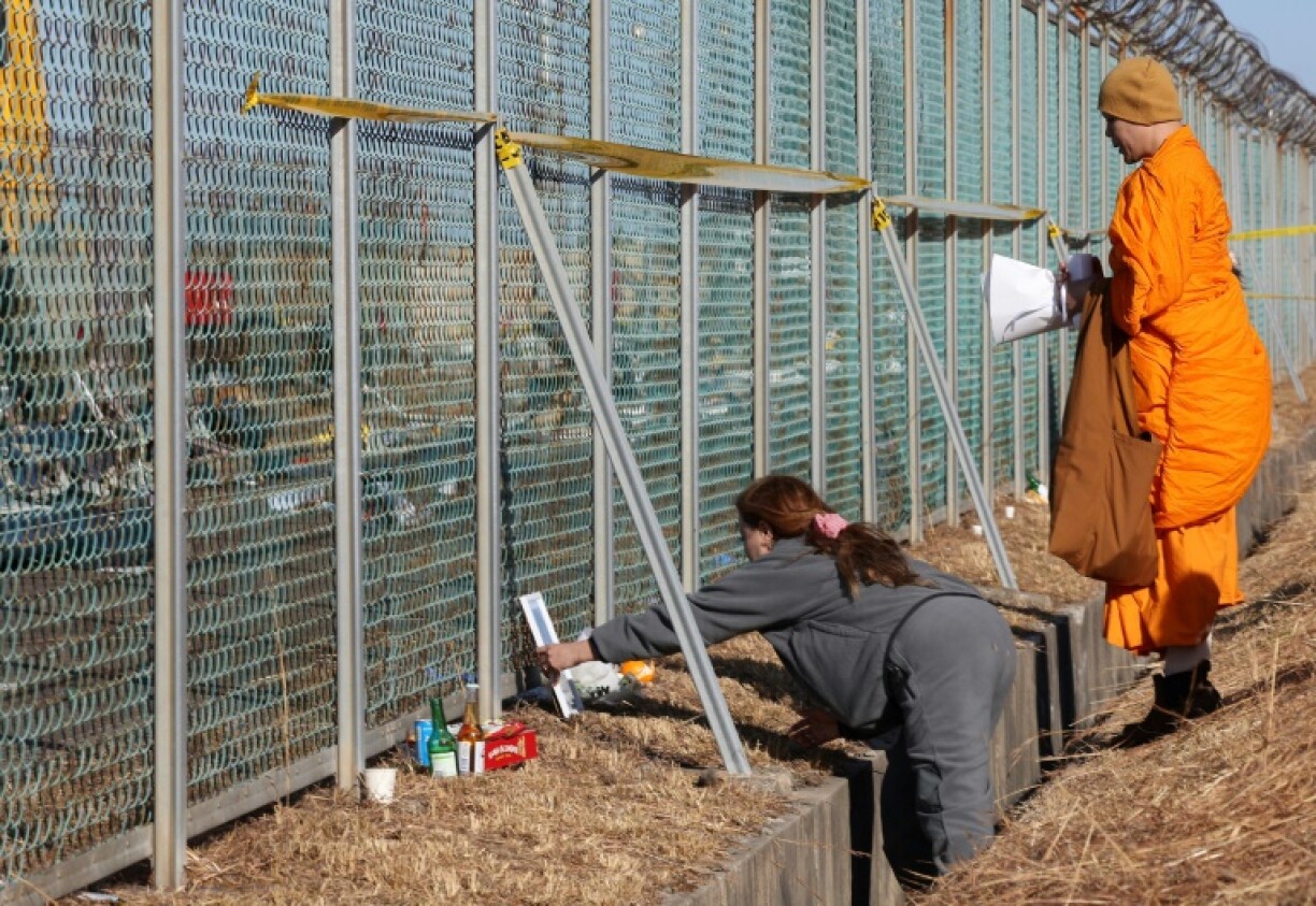 A relative (L) of a Thai passenger mourns at the scene where a Jeju Air Boeing 737-800 aircraft crashed and burst into flames at Muan International Airport