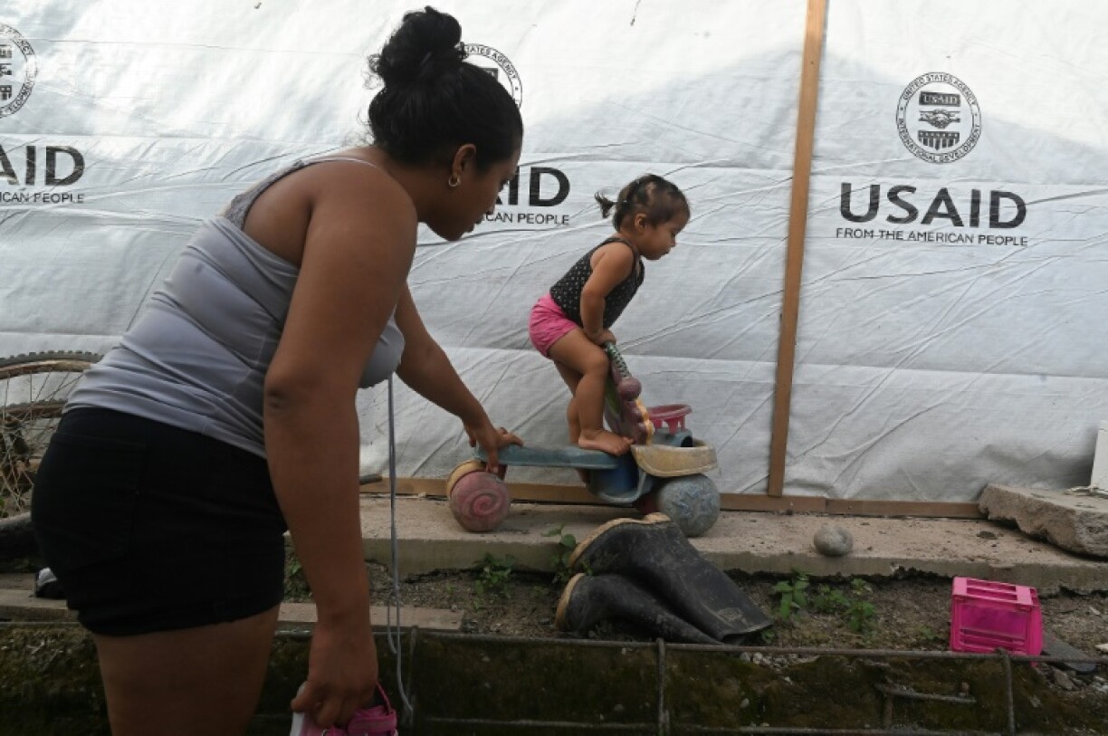 Sandra Ramos plays with her daughterat an improvised shack built with the help of the US Agency for the International Development (USAID) following hurricanes in in La Lima, Honduras, in July 2022
