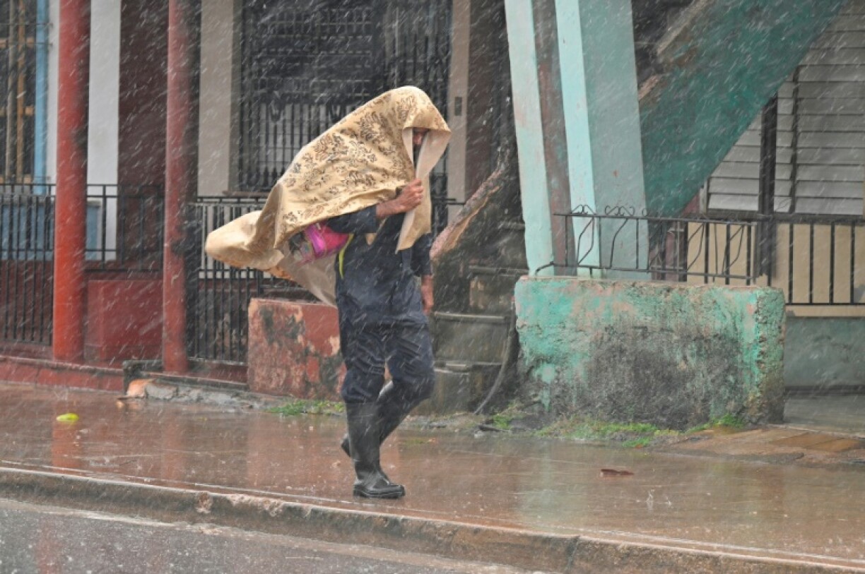 Un homme marche sous une pluie battante après l'arrivée de l'ouragan Rafael à Pueblo Candelaria, dans la province d'Artemisa, à 65 km à l'ouest de La Havane, le 6 novembre 2024