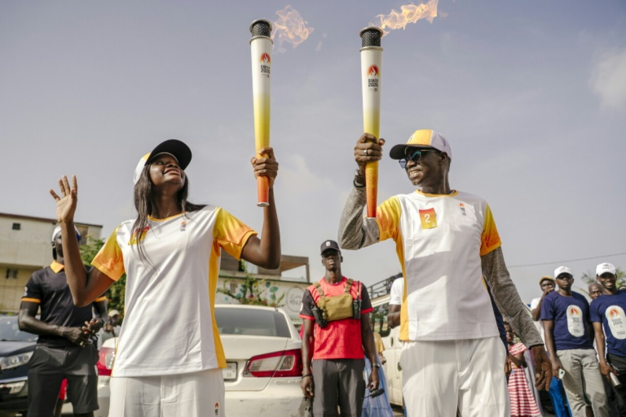 Torchbearers carry the Youth Olympic Flame during its tour through Dakar in September 2026
