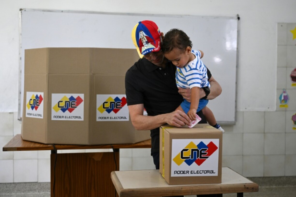 Venezuelan opposition candidate Henrique Capriles casts his vote while holding his son at a polling station in Caracas