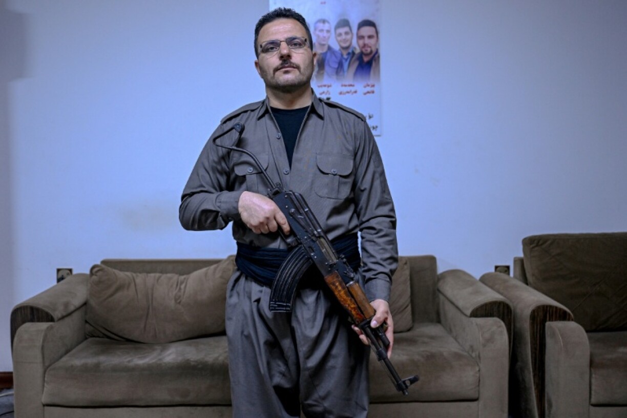 Aresto Pasbar, un Iranien qui a fui le pays après avoir rejoint les manifestations antigouvernementales de 2022, tient un fusil AK-47 dans une maison de Souleimaniyeh, le 13 mars 2026 en Irak
