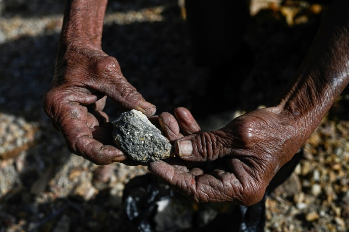 An artisanal miner holds ore extracted from an abandoned mine in El Salvador