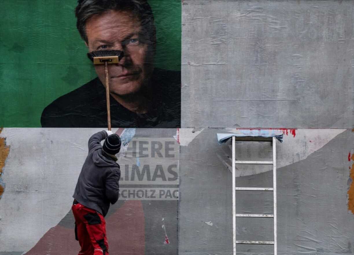 A worker puts up a campaign poster featuring a portrait of the Greens' main candidate Robert Habeck