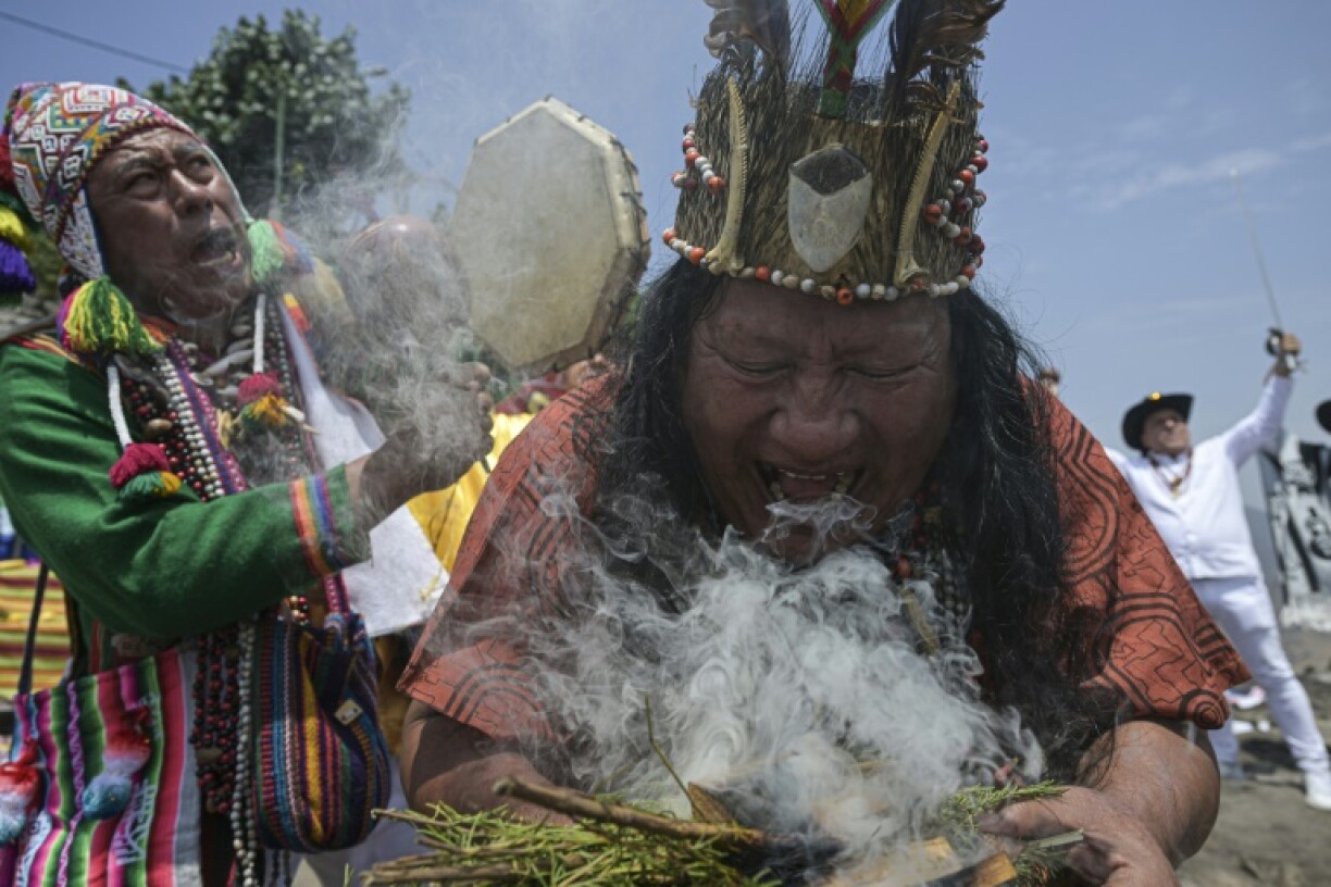Chantant, frappant des tambours, soufflant de la fumée... les chamans péruviens ont exécuté un rituel pour livrer leurs prédictions pour l'année à venir au sommet d'une colline au-dessus de Lima, le 27 décembre 2023