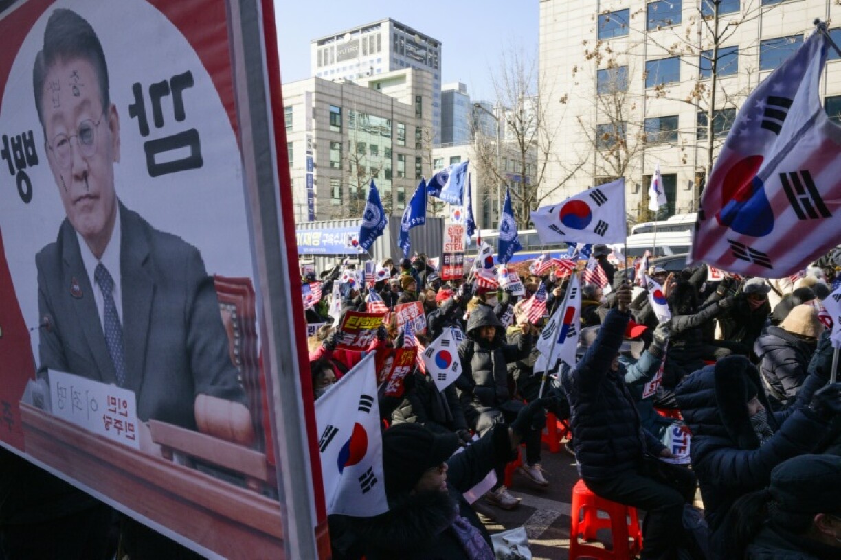 A defaced poster (L) of opposition Democratic Party leader Lee Jae-myung is displayed alongside supporters of South Korean leader Yoon Suk Yeol, during a rally near the Central District Court in Seoul on February 20, 2025