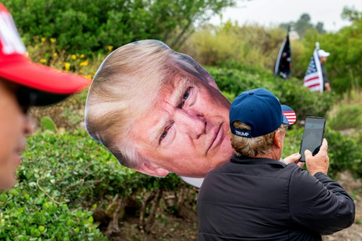 Des soutiens de l'ex-président et candidat républicain Donald Trump avec une pancarte à son image le 8 juin 2024, à Newport Beach, en Californie