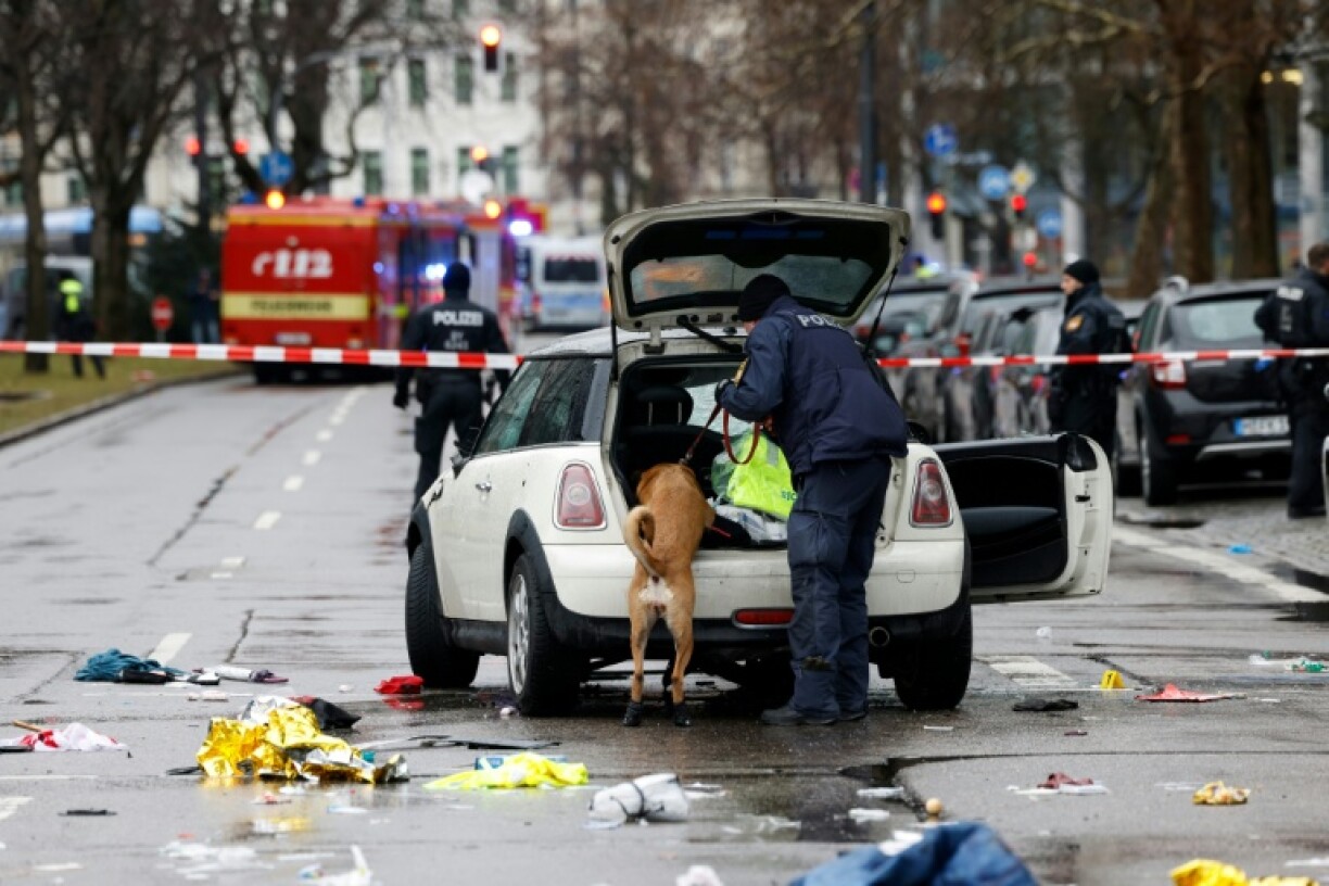 Un policier et son chien fouillent une voiture sur les lieux où un homme a foncé dans une foule dans la ville de Munich, le 13 février 2025, faisant deux morts et une quarantaine de blessés