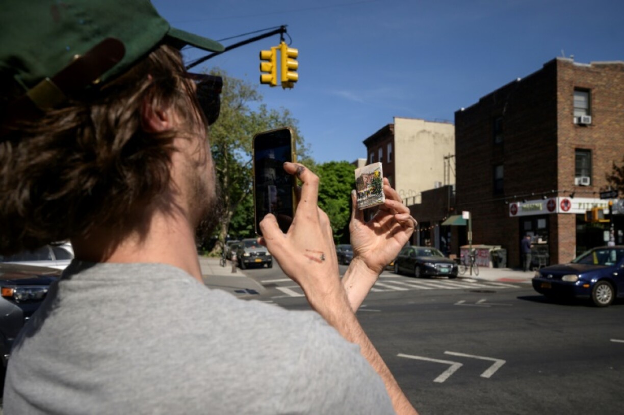 Le peintre Steve Wasterval prend une photo d'un de ses tableaux miniatures, le 25 mai 2021 dans le quartier de Greenpoint, à New York