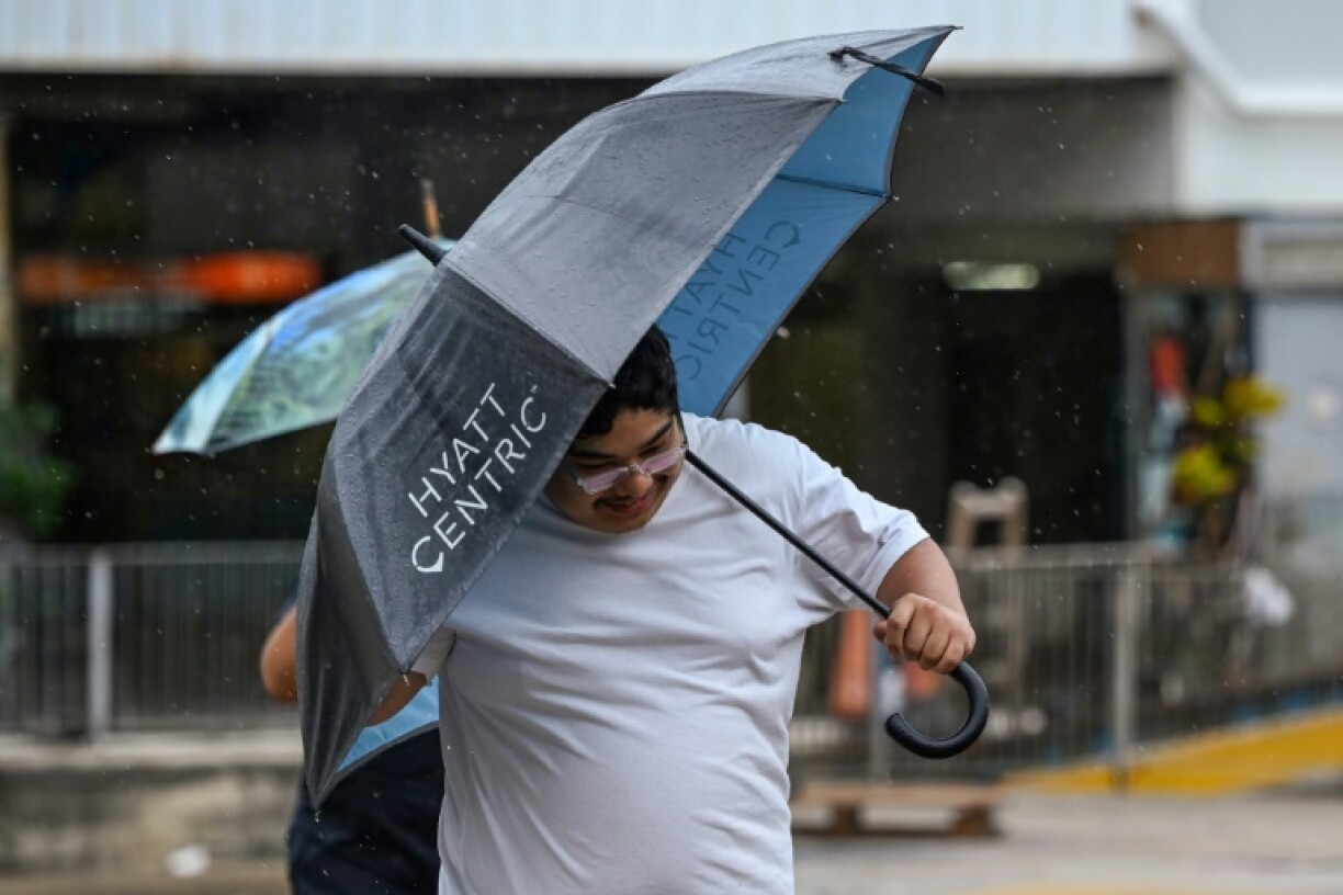 Un homme s'abrite de la pluie et du vent apportés par le typhon Saola à Hong Kong vendredi 1er septembre 2023