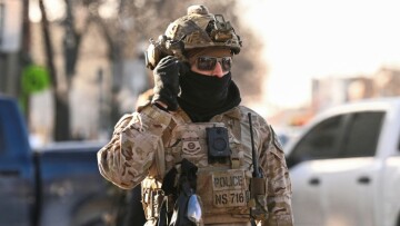 Un agent de la police aux frontières américaine devant des manifestants à Minneapolis, près du lieu où des agents fédéraux ont tué un homme par balle, le 24 janvier 2026