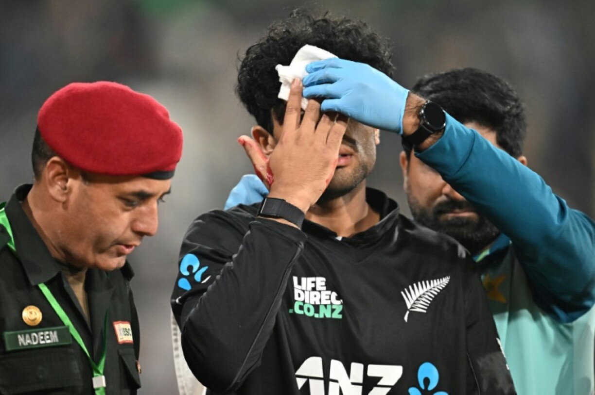 New Zealand's Rachin Ravindra leaves the field after being hit on the head by the ball