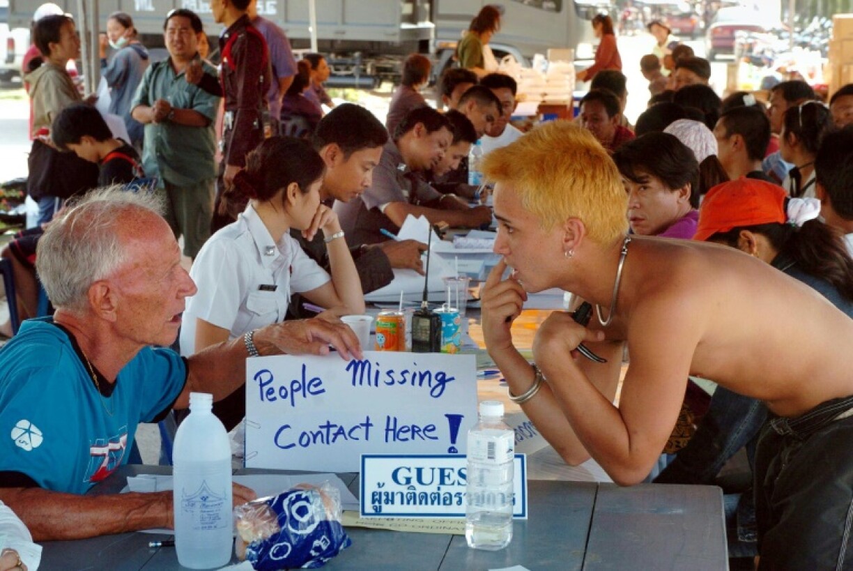 Canadian volunteer Michael Furlong (L) assists Thai and foreign tourists looking for missing relatives outside the government Patong Hospital in Phuket island, December 28, 2004