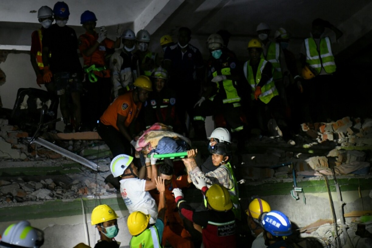 Rescue workers carry a victim trapped under the rubble of a destroyed building in Mandalay