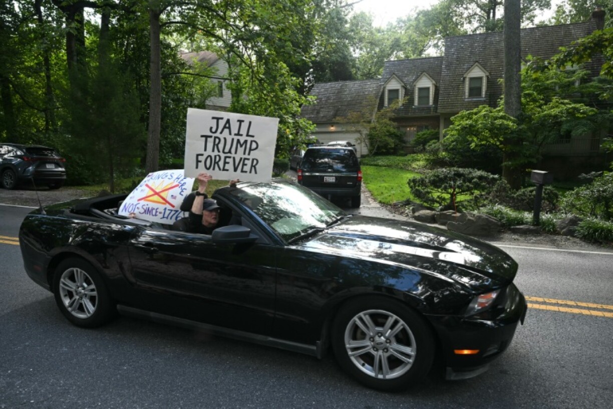 Protestors holding signs drive past the home of John Bolton, President Donald Trump's former national security adviser