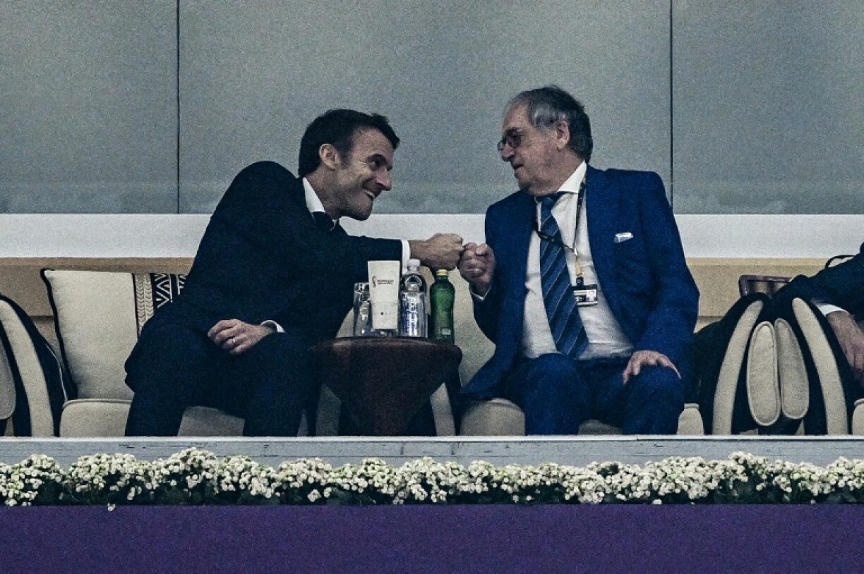 Le président français Emmanuel Macron (G) tape du poing avec le président de la Fédération française de football, Noël Le Graët, lors de la demi-finale de la Coupe du monde de football Qatar 2022 à Doha, le 14 décembre 2022